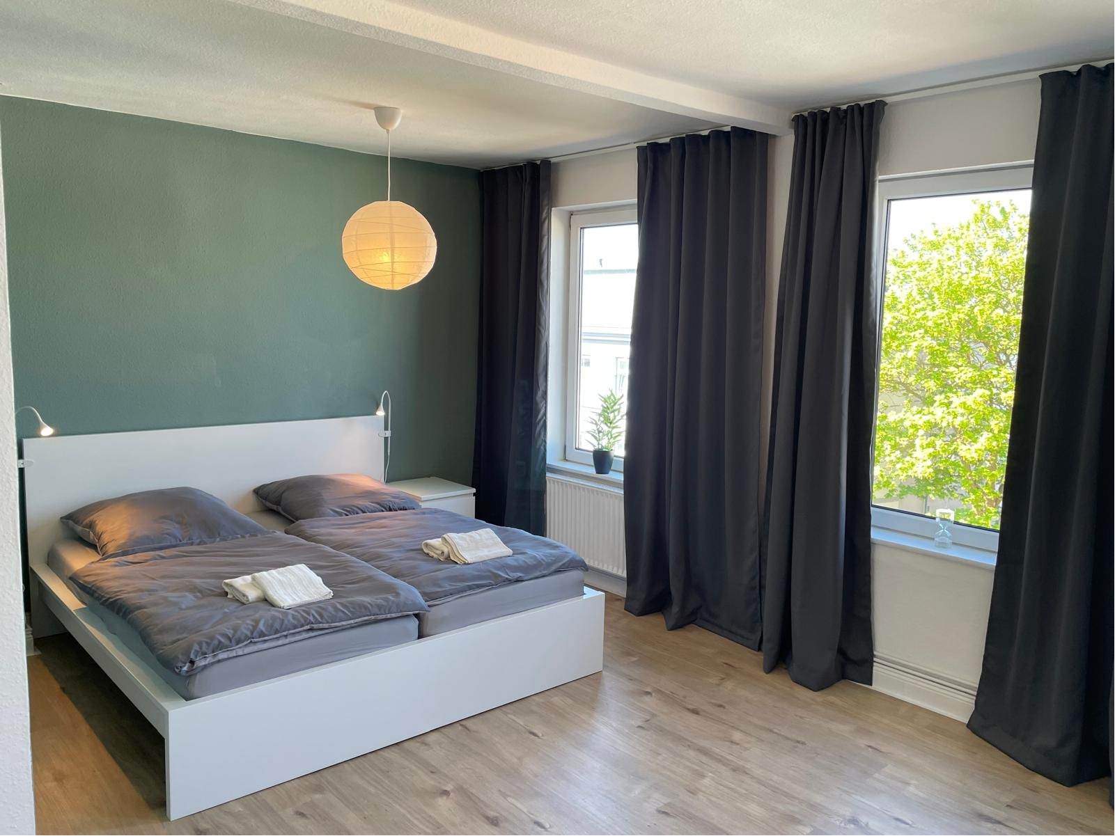 Helles Schlafzimmer mit Doppelbett und grüner Wand