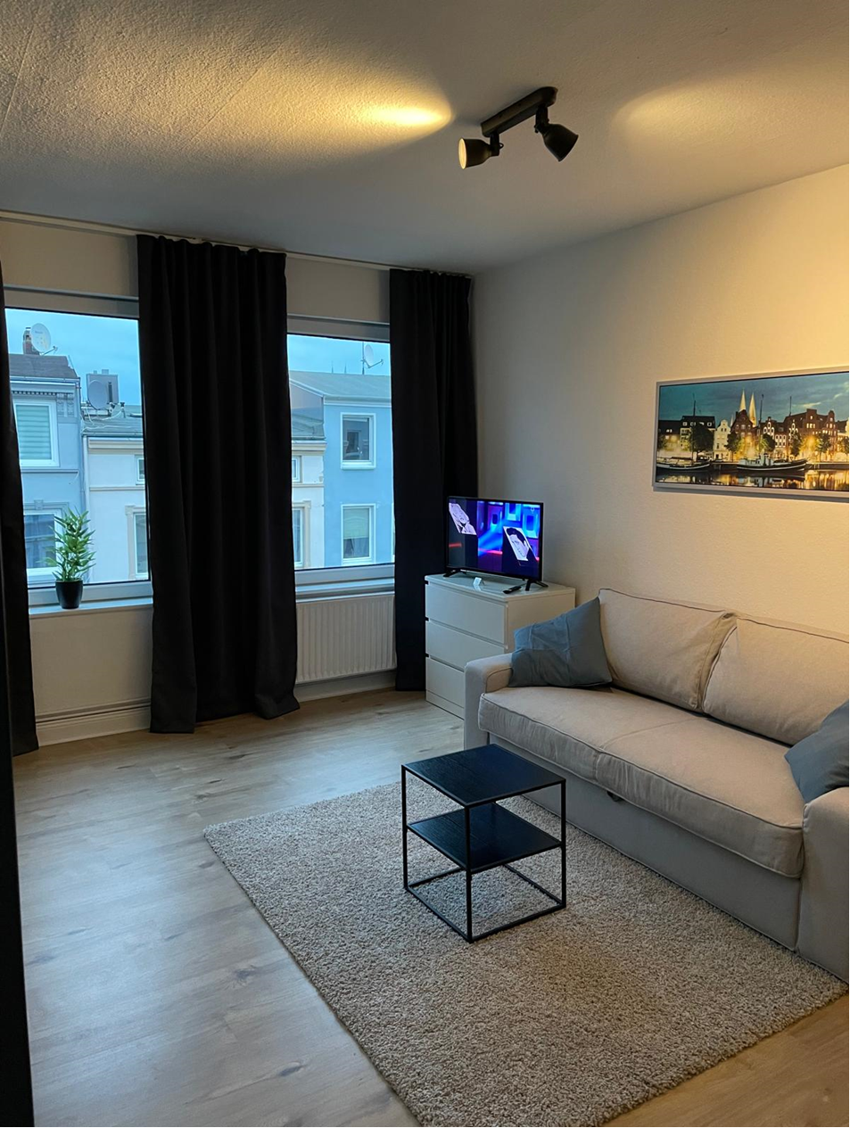 Gemütliches Wohnzimmer mit Fernseher und Straßenblick