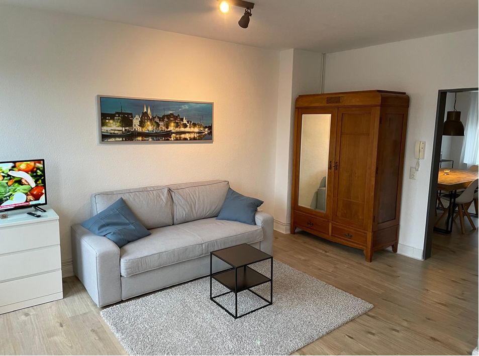 Wohnzimmer mit Schlafcouch und antikem Kleiderschrank